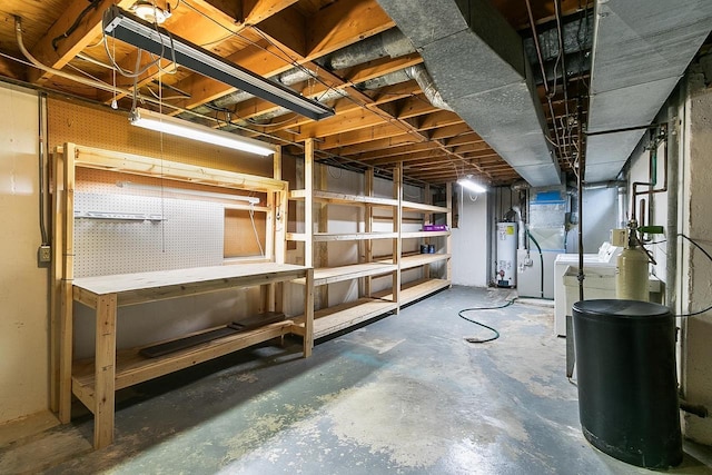 unfinished below grade area featuring water heater, separate washer and dryer, and a workshop area