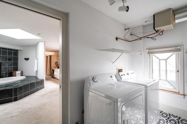 clothes washing area with a skylight, light carpet, laundry area, and washing machine and dryer