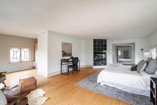 bedroom with baseboards, wood finished floors, and a fireplace