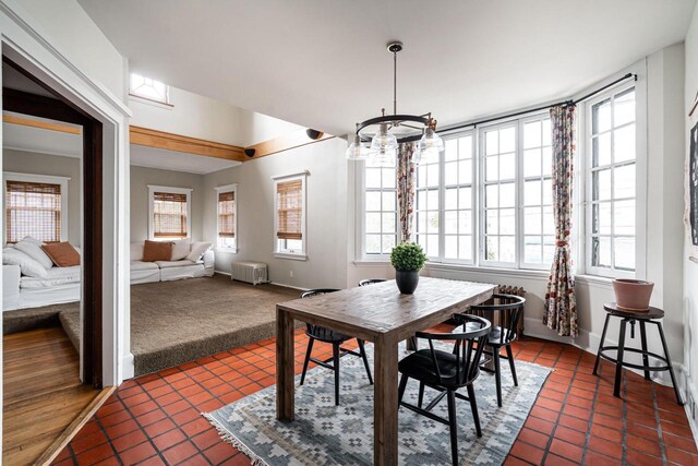 dining space with dark carpet, a notable chandelier, baseboards, radiator, and dark tile patterned floors