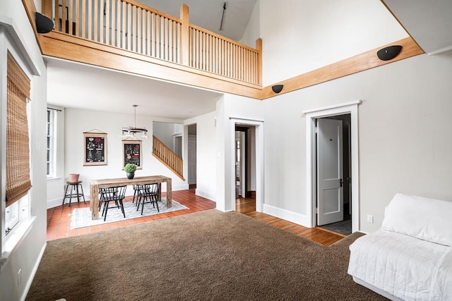 living area featuring baseboards, an inviting chandelier, a high ceiling, and carpet