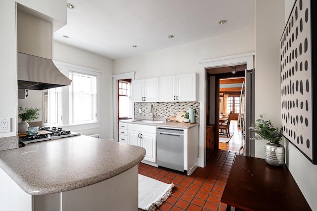 kitchen featuring white cabinets, a sink, appliances with stainless steel finishes, a peninsula, and backsplash