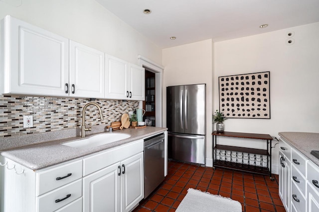 kitchen featuring white cabinetry, backsplash, appliances with stainless steel finishes, and a sink