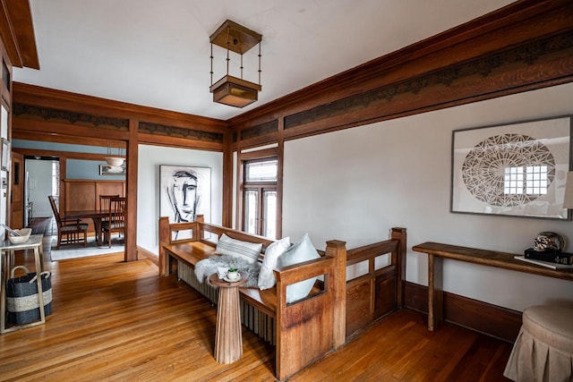 interior space with ornamental molding, wood finished floors, and baseboards