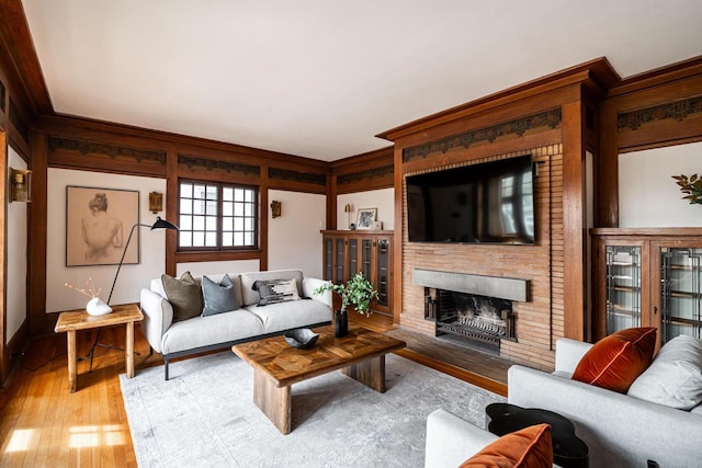 living room with baseboards, wood finished floors, ornamental molding, and a fireplace