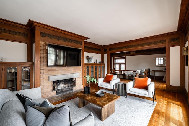 living area featuring ornamental molding, hardwood / wood-style flooring, and a fireplace