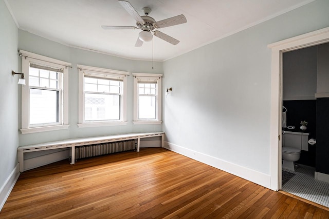 empty room featuring light wood-type flooring, crown molding, a ceiling fan, baseboards, and plenty of natural light