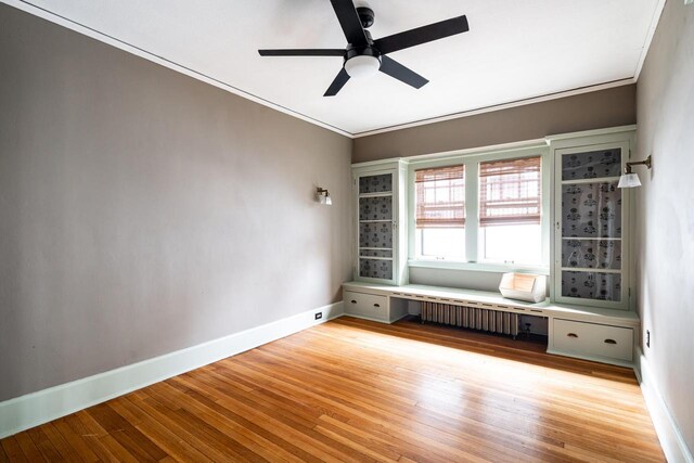 unfurnished room featuring crown molding, light wood-style floors, ceiling fan, baseboards, and radiator
