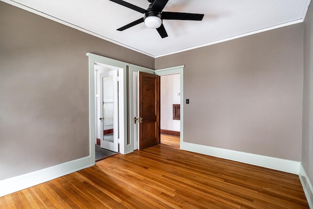 interior space with crown molding, ceiling fan, ensuite bathroom, hardwood / wood-style floors, and baseboards