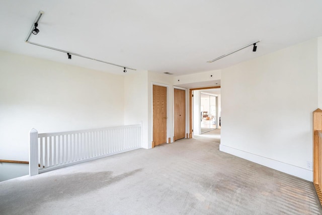 spare room with track lighting and light carpet