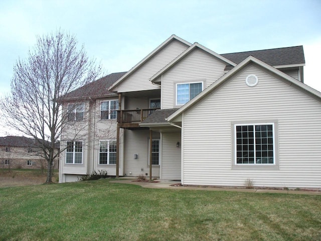 view of front of property with a front yard, a balcony, and a shingled roof