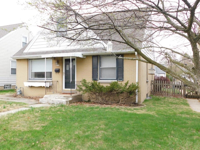 view of front of house with a front yard, fence, and brick siding