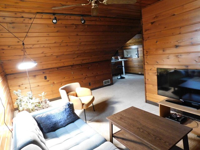 living room with lofted ceiling, wood walls, visible vents, track lighting, and carpet