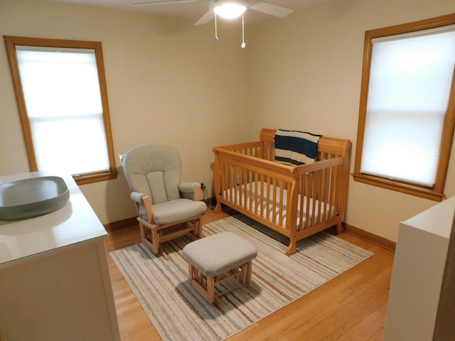 bedroom with a crib, multiple windows, and light wood-style flooring