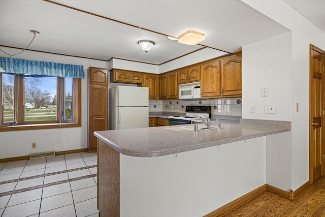 2500 S Brookside Pkwy, New Berlin, WI 53151 - kitchen with a sink, white appliances, brown cabinetry, a peninsula, and baseboards
