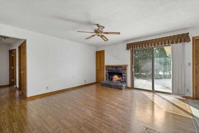 2500 S Brookside Pkwy, New Berlin, WI 53151 - unfurnished living room with a textured ceiling, baseboards, a brick fireplace, wood finished floors, and a ceiling fan