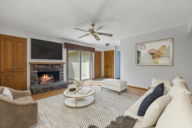2500 S Brookside Pkwy, New Berlin, WI 53151 - living room featuring a brick fireplace, a ceiling fan, baseboards, a textured ceiling, and wood finished floors