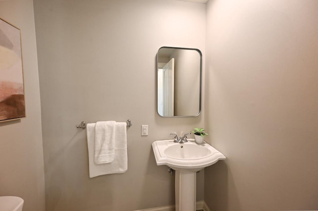 half bath featuring baseboards and toilet
