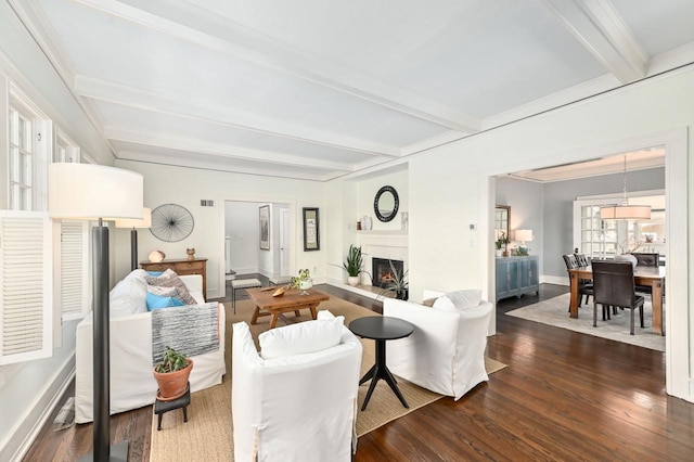 living room featuring dark wood-style flooring, visible vents, baseboards, beamed ceiling, and a lit fireplace