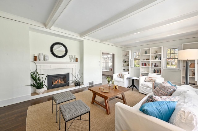 living area with baseboards, beamed ceiling, a glass covered fireplace, and wood finished floors