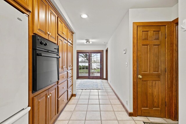 2108 Woodlawn Ln, Appleton, WI 54914 - kitchen featuring freestanding refrigerator, brown cabinets, black oven, baseboards, and light tile patterned flooring