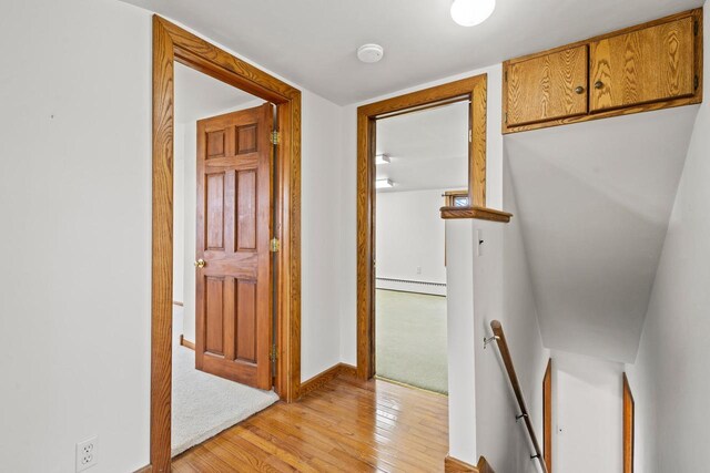 2108 Woodlawn Ln, Appleton, WI 54914 - hallway featuring a baseboard heating unit, an upstairs landing, light wood-style flooring, and baseboards