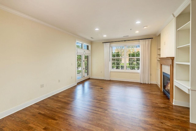 unfurnished living room with a glass covered fireplace, baseboards, ornamental molding, and dark wood-style floors