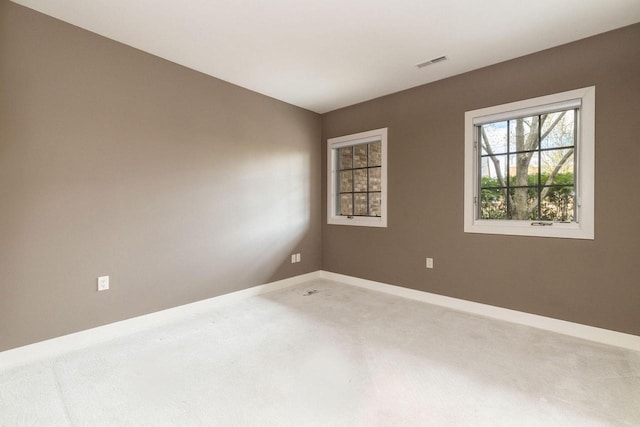 carpeted spare room with visible vents and baseboards
