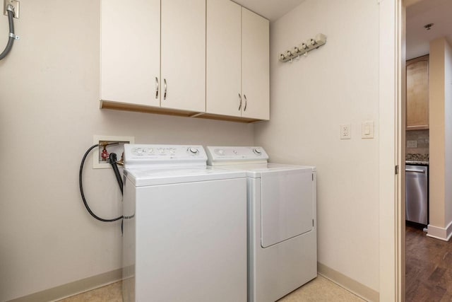 washroom featuring cabinet space, baseboards, wood finished floors, and washing machine and clothes dryer