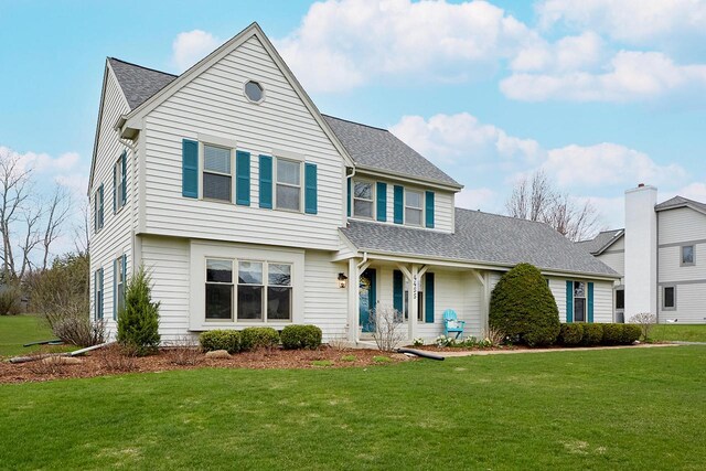 traditional home featuring roof with shingles and a front lawn