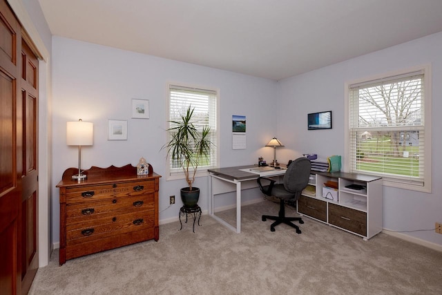 office featuring light colored carpet, a healthy amount of sunlight, and baseboards