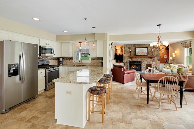 kitchen with tasteful backsplash, white cabinets, a sink, stainless steel appliances, and a peninsula