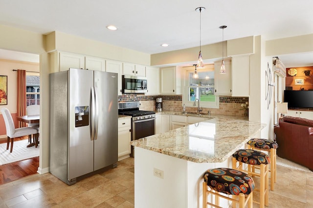 kitchen featuring appliances with stainless steel finishes, a peninsula, decorative backsplash, and a sink
