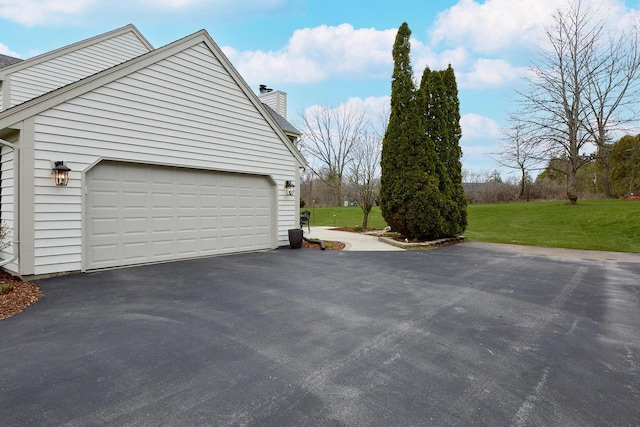 view of home's exterior featuring driveway, a yard, a garage, and a chimney