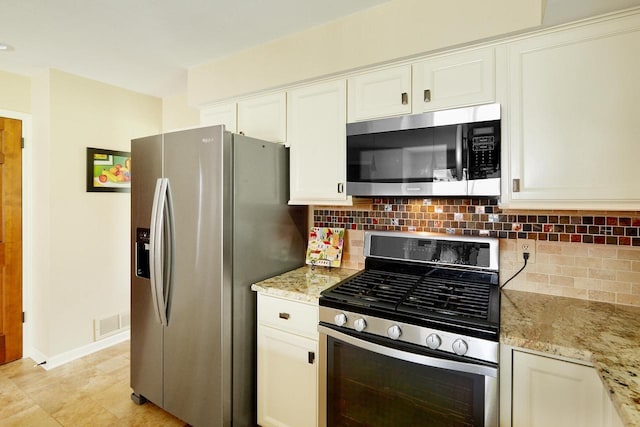 kitchen with light stone countertops, stainless steel appliances, backsplash, white cabinetry, and visible vents