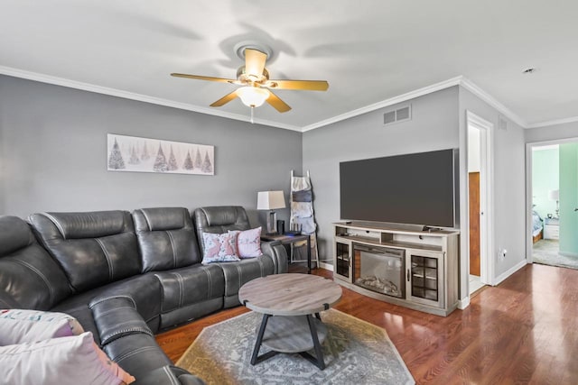 living area featuring crown molding, visible vents, baseboards, wood finished floors, and a ceiling fan