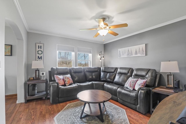 living area featuring ornamental molding, arched walkways, ceiling fan, and wood finished floors
