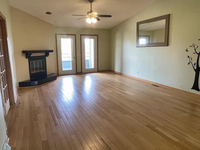 unfurnished living room with ceiling fan, visible vents, baseboards, a fireplace, and wood finished floors
