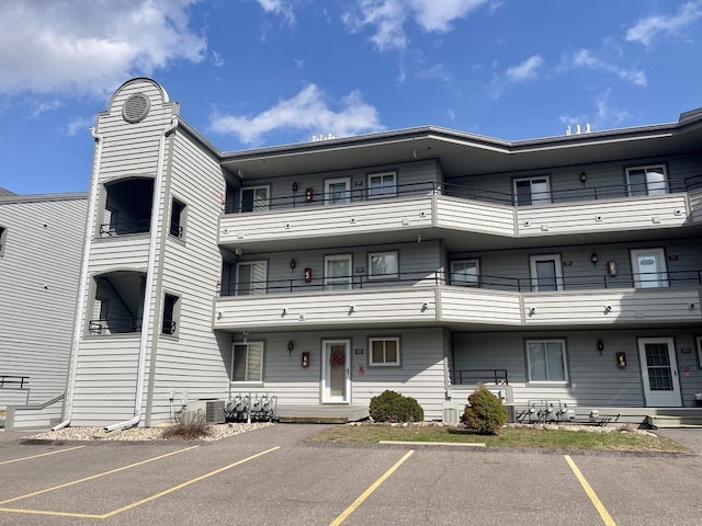 view of building exterior with central AC and uncovered parking