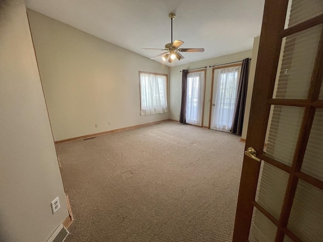 spare room featuring a ceiling fan, light carpet, and baseboards