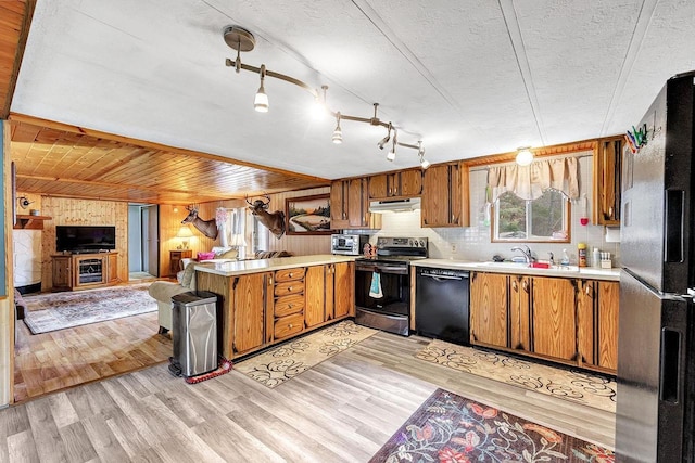 11689 Eagle Bluff Ln, Crivitz, WI 54114 - kitchen with a sink, under cabinet range hood, brown cabinetry, black appliances, and a peninsula