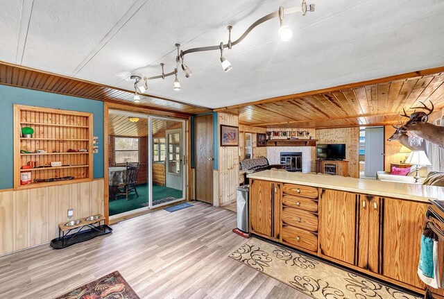11689 Eagle Bluff Ln, Crivitz, WI 54114 - kitchen featuring wooden walls, light countertops, light wood finished floors, a glass covered fireplace, and open floor plan
