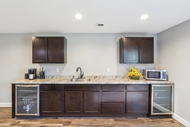 911 Fawn Ct, Wisconsin Dells, WI 53965 - bar area with beverage cooler, stainless steel microwave, a sink, baseboards, and wood finished floors
