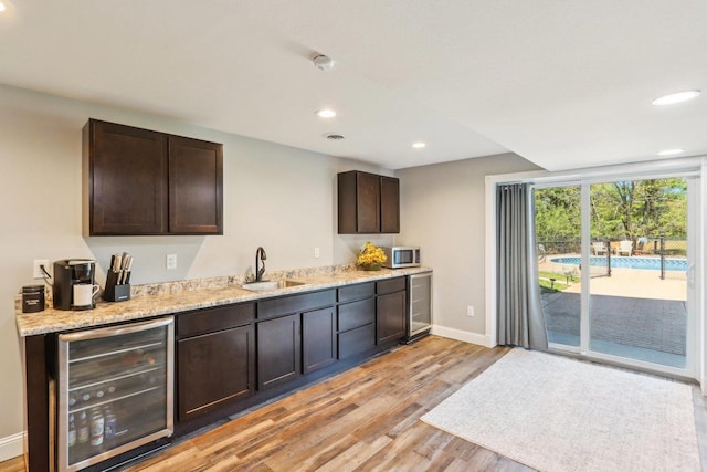 911 Fawn Ct, Wisconsin Dells, WI 53965 - kitchen featuring beverage cooler, stainless steel microwave, a sink, light wood-type flooring, and recessed lighting
