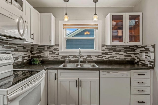 kitchen with white cabinetry, dark countertops, white appliances, and a sink