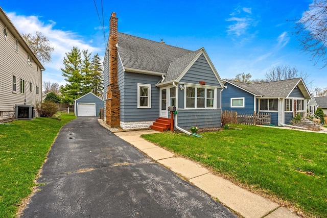 view of front of house with a shingled roof, an outdoor structure, cooling unit, a detached garage, and driveway