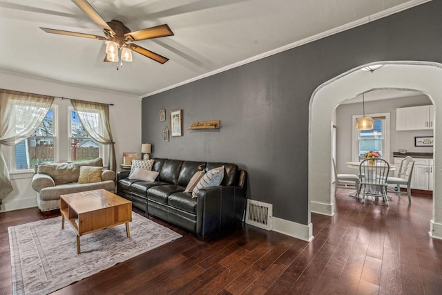 living area featuring arched walkways, visible vents, ceiling fan, and dark wood-style flooring