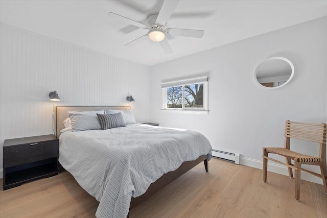 bedroom featuring light wood-style floors, ceiling fan, baseboard heating, and baseboards