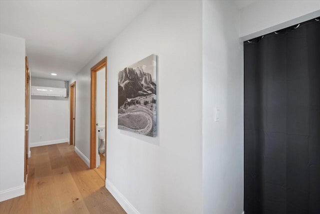 hall with recessed lighting, an AC wall unit, baseboards, and light wood-type flooring