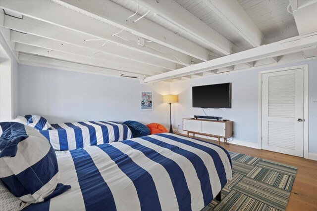 bedroom with beamed ceiling, wood finished floors, and baseboards